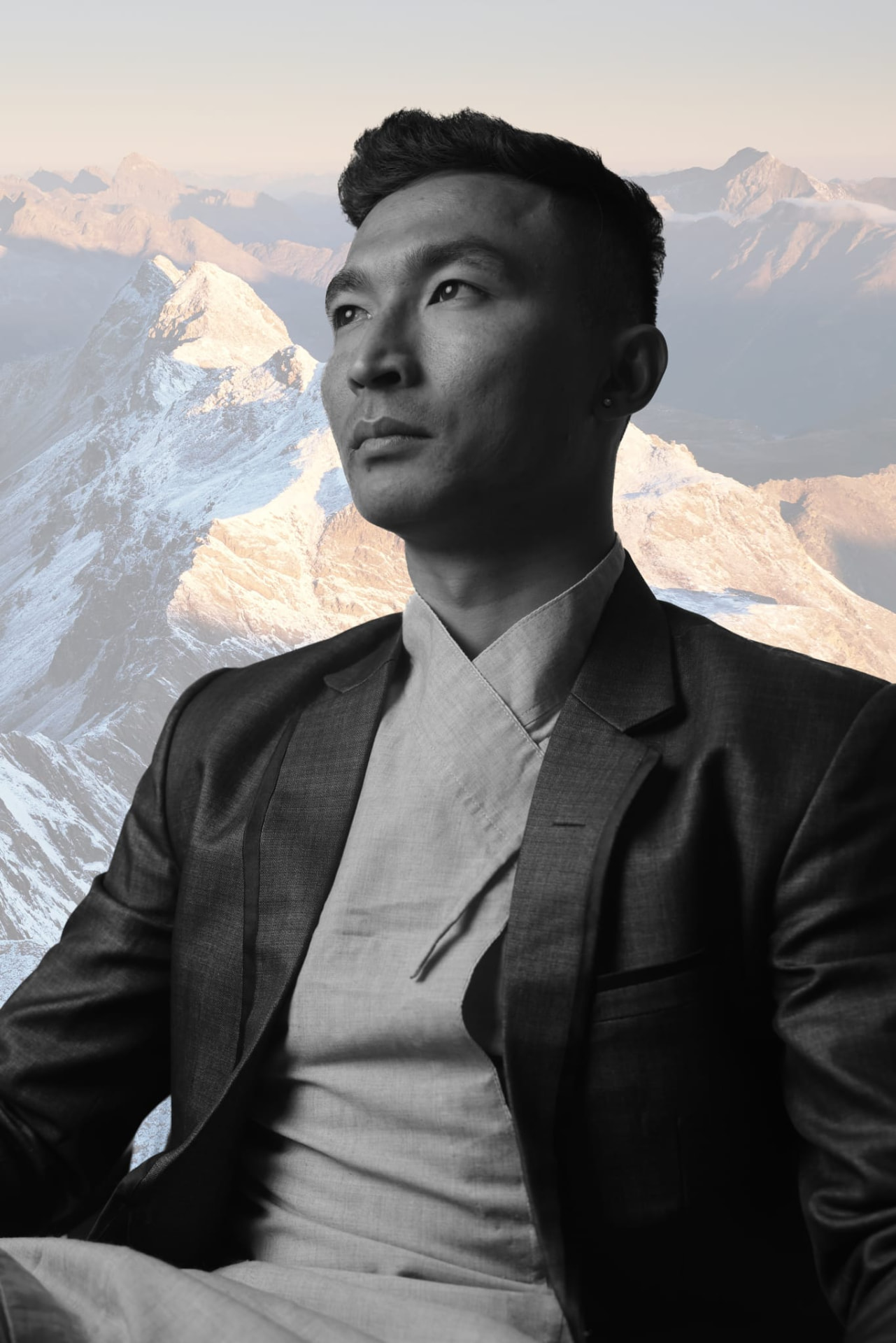 A black and white portrait of Sajan Dangol set against snow-covered mountains