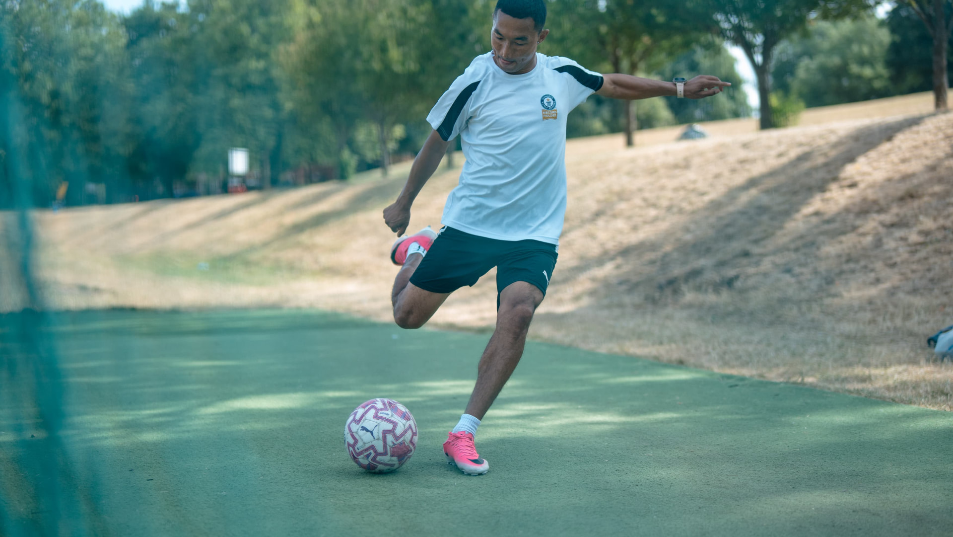 Sajan Dangol striking a football on a grass pitch