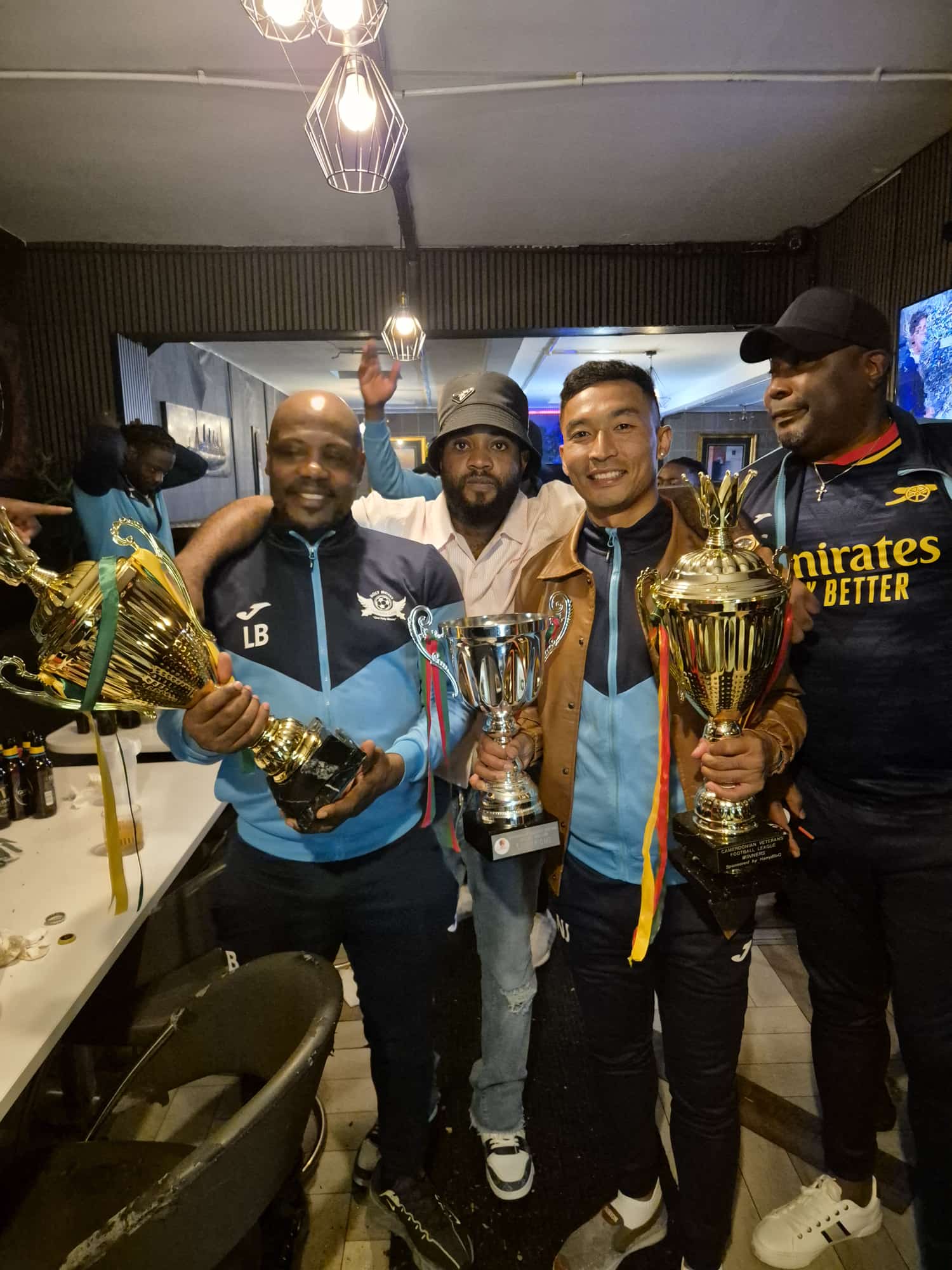 Sajan Dangol celebrating a league title with teammates holding three trophies