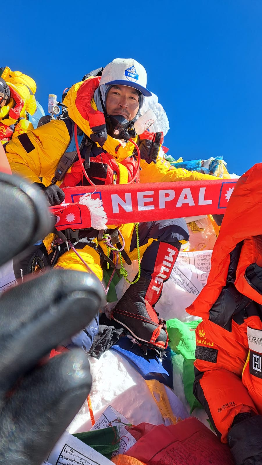 Sajan Dangol on the summit of Mount Everest holding a Nepal scarf
