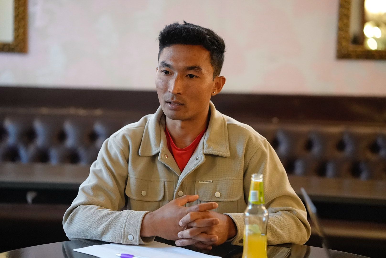 Sajan Dangol seated at a table in a lounge, speaking during a conversation